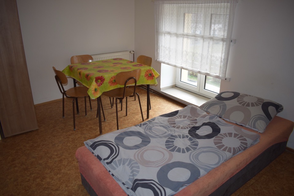 Pokoj ve staré budově s lůžkem, stolem a čtyřmi židlemi